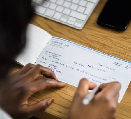 african woman signing bank check or paycheck