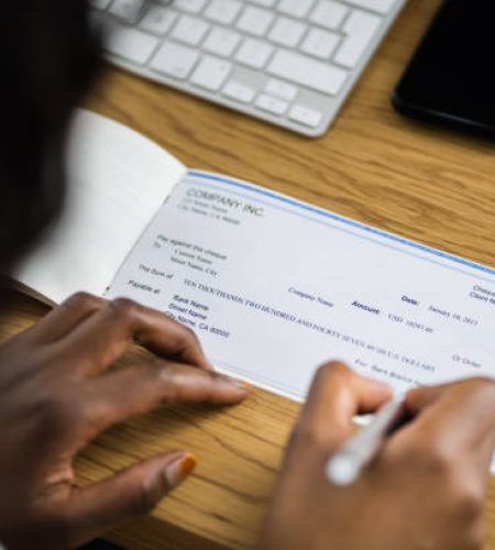 african woman signing bank check or paycheck